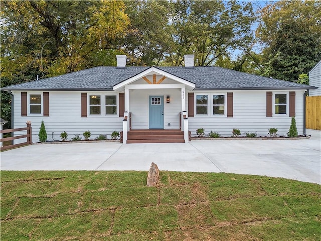 ranch-style house featuring roof with shingles, a chimney, a front yard, and fence