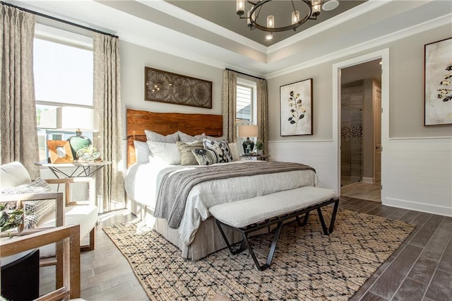 bedroom featuring a tray ceiling, crown molding, and an inviting chandelier