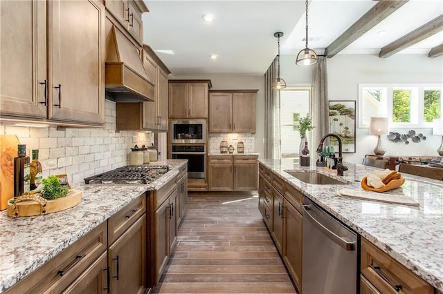 kitchen with pendant lighting, sink, beam ceiling, light stone counters, and stainless steel appliances