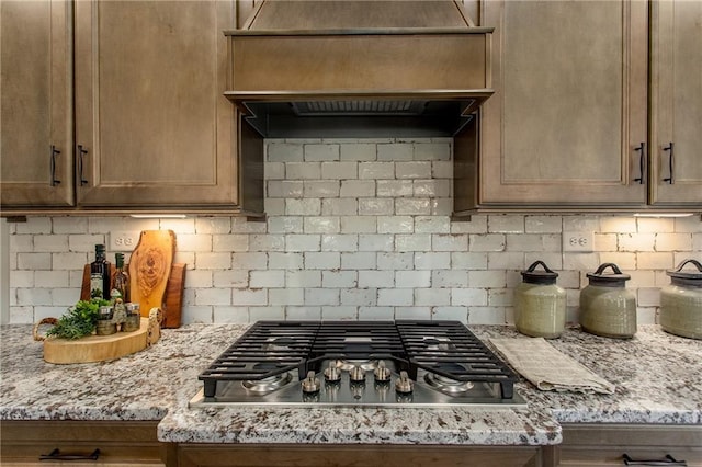 kitchen featuring decorative backsplash, light stone countertops, and stainless steel gas stovetop