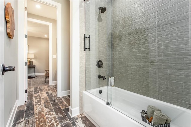 bathroom with hardwood / wood-style floors and shower / bath combination with glass door