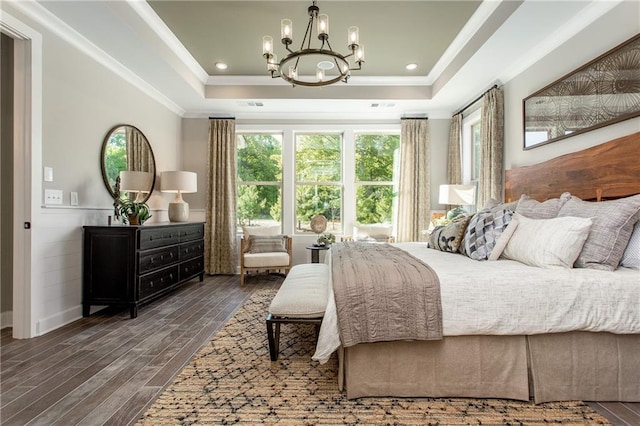 bedroom featuring dark hardwood / wood-style floors, a raised ceiling, crown molding, and an inviting chandelier