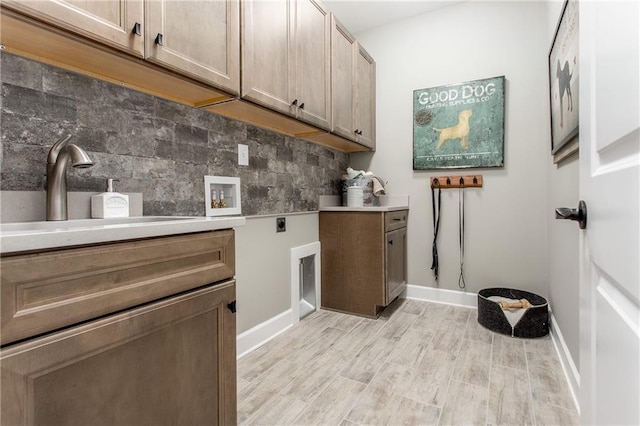 laundry room with sink, cabinets, hookup for an electric dryer, hookup for a washing machine, and light hardwood / wood-style floors