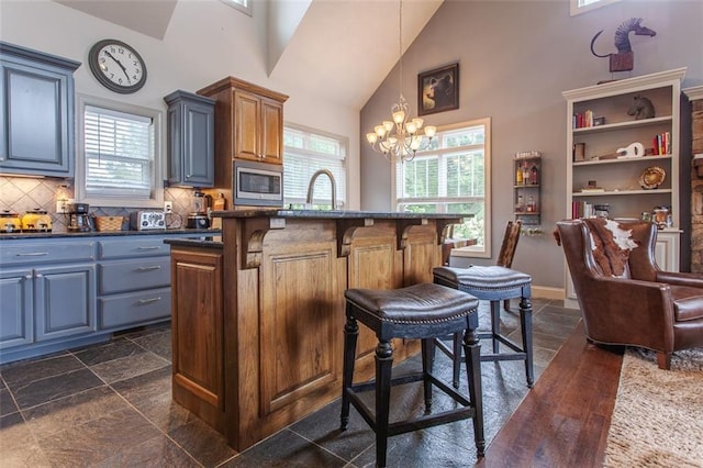 kitchen featuring a kitchen bar, an inviting chandelier, pendant lighting, and a wealth of natural light