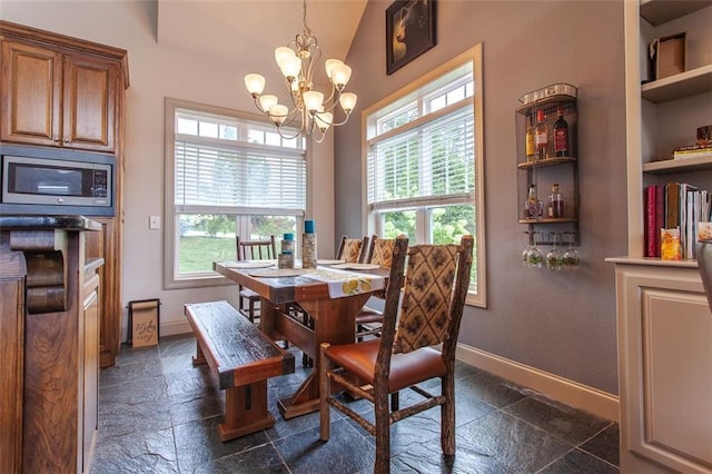 dining space featuring an inviting chandelier, a wealth of natural light, vaulted ceiling, and built in shelves