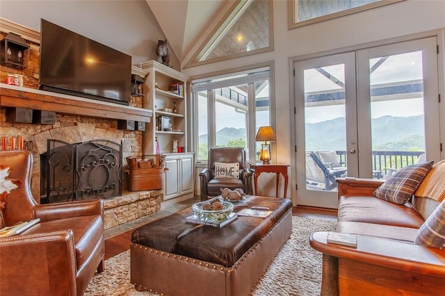 living room featuring a stone fireplace, light wood-type flooring, high vaulted ceiling, and a mountain view