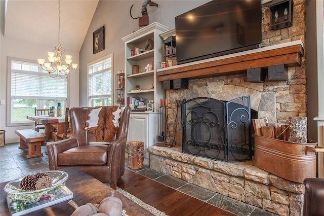 living room featuring high vaulted ceiling, a stone fireplace, dark hardwood / wood-style flooring, built in shelves, and a notable chandelier