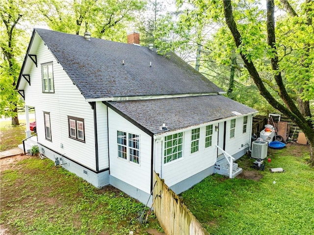 rear view of house featuring crawl space, a chimney, central air condition unit, and a shingled roof