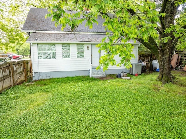 rear view of property featuring entry steps, central AC, and a shingled roof