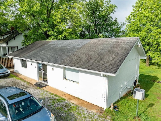 view of front of house featuring a shingled roof, central AC, and stucco siding