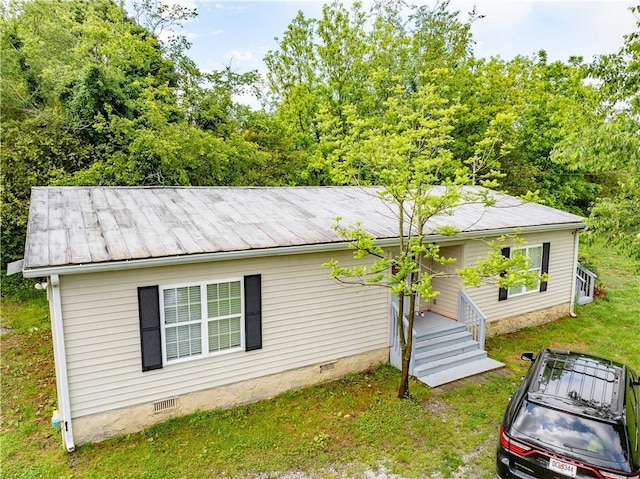 view of side of home with crawl space and a yard