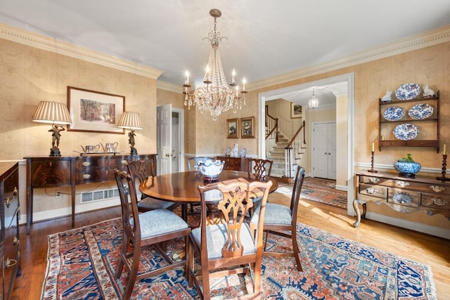 dining space with crown molding, hardwood / wood-style floors, and an inviting chandelier