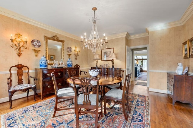 dining space with hardwood / wood-style flooring, crown molding, and an inviting chandelier