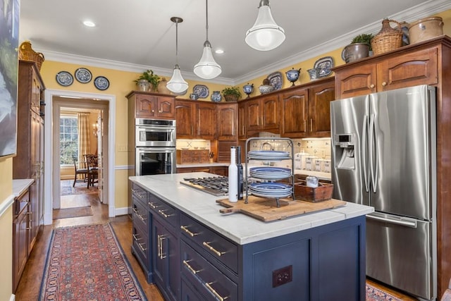 kitchen with pendant lighting, tasteful backsplash, ornamental molding, stainless steel appliances, and a center island with sink