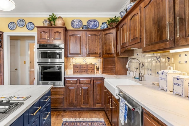 kitchen with appliances with stainless steel finishes, hardwood / wood-style floors, tasteful backsplash, sink, and ornamental molding