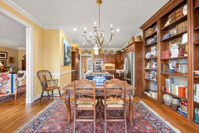 dining space with an inviting chandelier, hardwood / wood-style floors, and ornamental molding