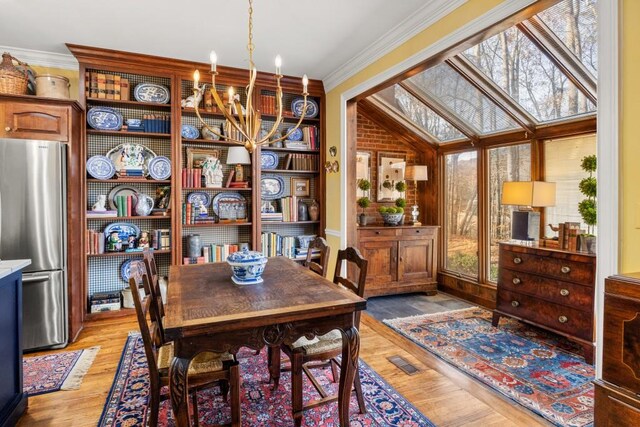 dining space with hardwood / wood-style flooring, ornamental molding, and a chandelier