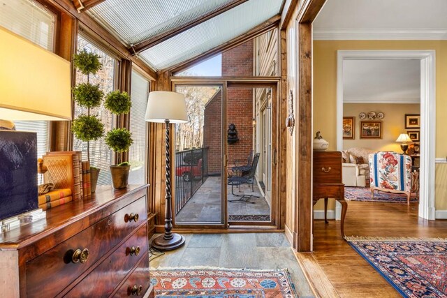 doorway to outside featuring ornamental molding, light hardwood / wood-style floors, and vaulted ceiling with beams