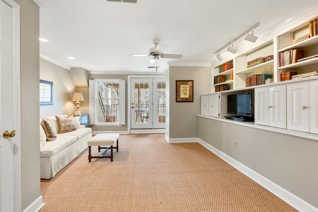 carpeted living room featuring track lighting, ornamental molding, and ceiling fan