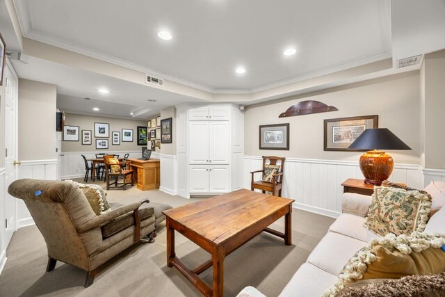 living area featuring light carpet, ornamental molding, and a raised ceiling