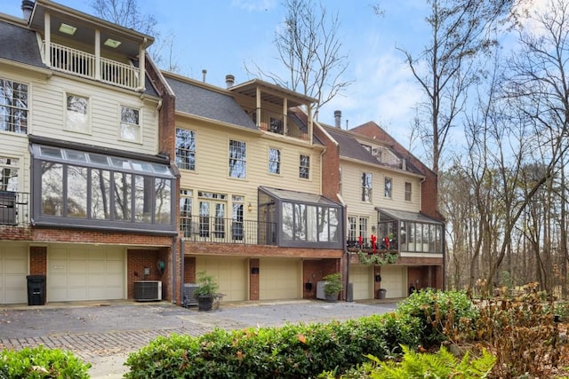 rear view of property featuring a garage and central AC unit