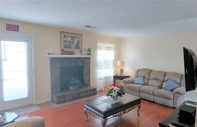 living room with plenty of natural light and a stone fireplace