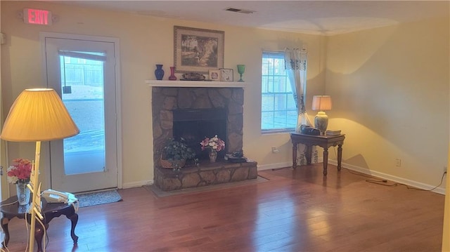 living room featuring wood-type flooring and a stone fireplace