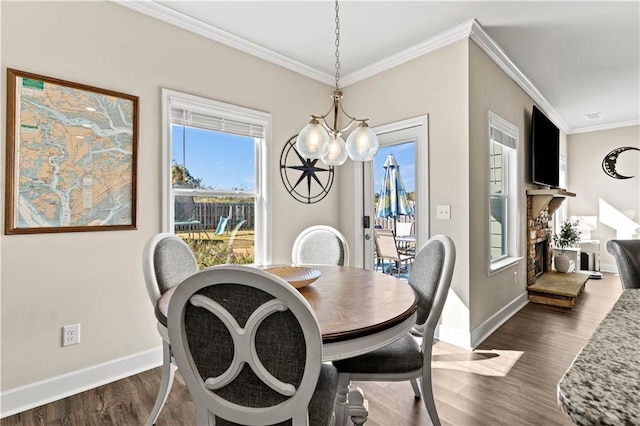 dining space featuring dark wood-type flooring, a notable chandelier, ornamental molding, and a fireplace