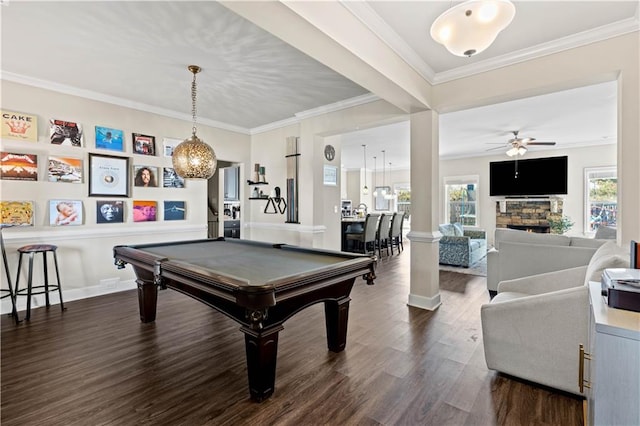 game room with ornamental molding, dark hardwood / wood-style floors, a stone fireplace, and billiards