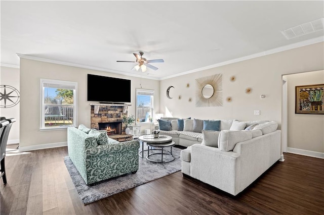 living room with a stone fireplace, crown molding, dark hardwood / wood-style floors, and ceiling fan