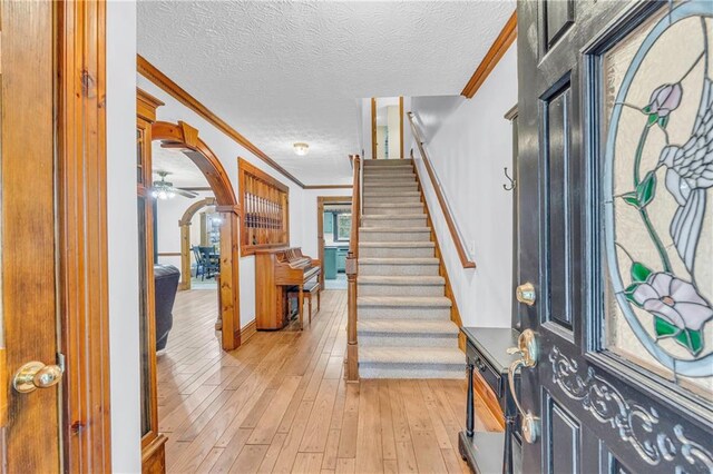 entryway with ornamental molding, a textured ceiling, ceiling fan, and light hardwood / wood-style floors