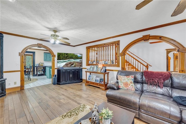 living room with hardwood / wood-style floors, ceiling fan, ornamental molding, and a textured ceiling