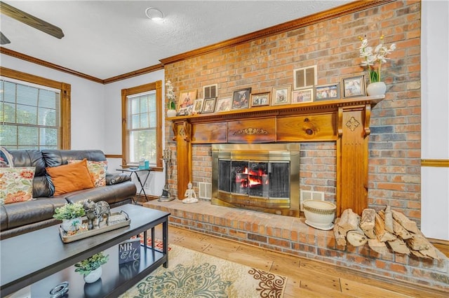 living room featuring hardwood / wood-style flooring, a fireplace, ornamental molding, and a healthy amount of sunlight