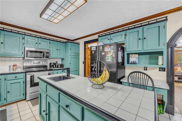 kitchen with light tile patterned floors, tile countertops, appliances with stainless steel finishes, crown molding, and sink