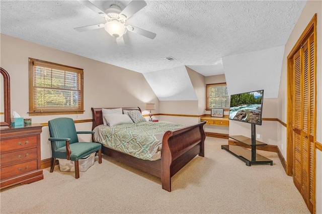 bedroom with a textured ceiling, light colored carpet, ceiling fan, and a closet