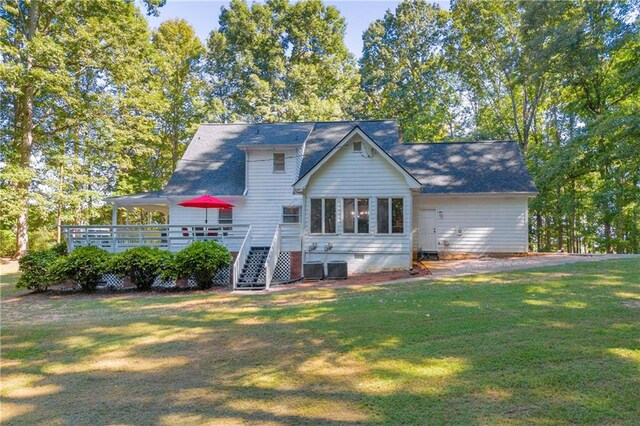 rear view of property featuring a lawn and a deck