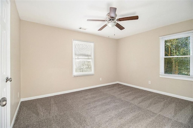 carpeted empty room with visible vents, baseboards, and ceiling fan