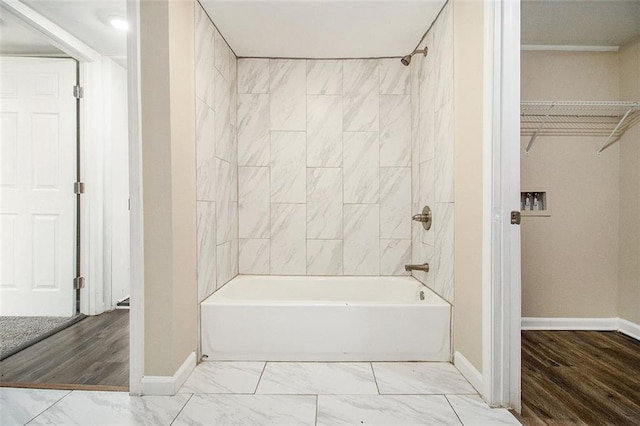 full bath with a spacious closet, marble finish floor, bathing tub / shower combination, and baseboards