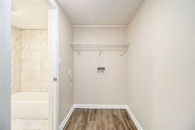 clothes washing area featuring hookup for a washing machine, wood finished floors, baseboards, and laundry area