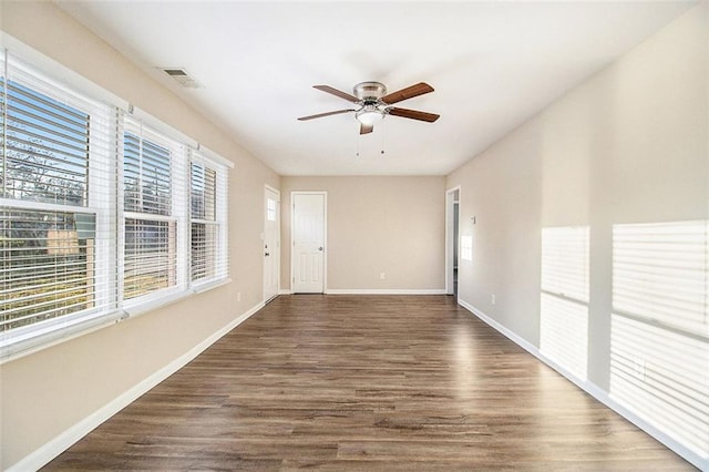 spare room featuring dark wood finished floors, visible vents, baseboards, and ceiling fan