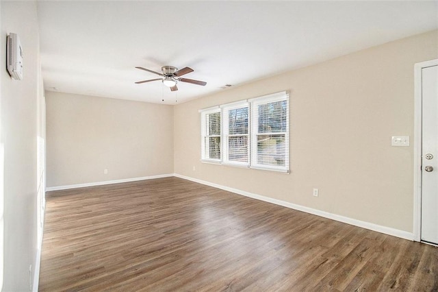 unfurnished room with baseboards, wood finished floors, and a ceiling fan