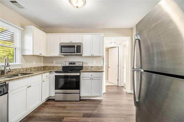 kitchen featuring dark wood-style floors, visible vents, a sink, stainless steel appliances, and white cabinets