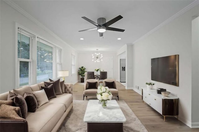 living room featuring ceiling fan with notable chandelier, light hardwood / wood-style flooring, and crown molding