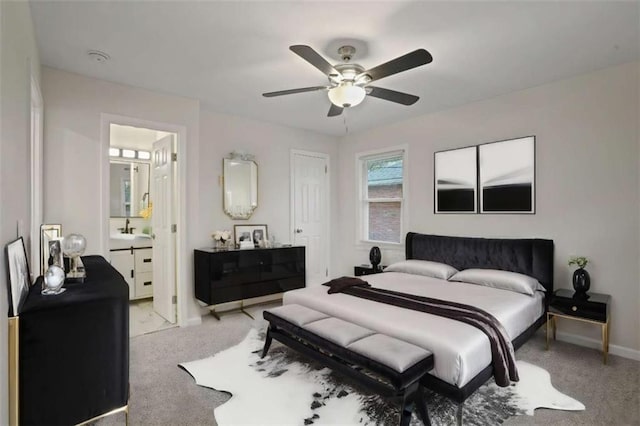 bedroom featuring sink, ceiling fan, light carpet, and ensuite bath