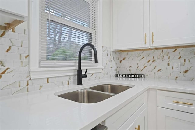 interior space with light stone counters, sink, white cabinetry, and tasteful backsplash