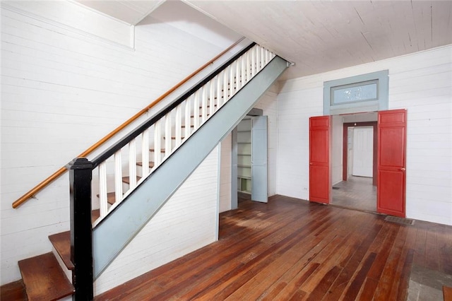 stairs with hardwood / wood-style flooring and wood walls