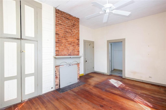 unfurnished living room with dark hardwood / wood-style flooring, a brick fireplace, and ceiling fan