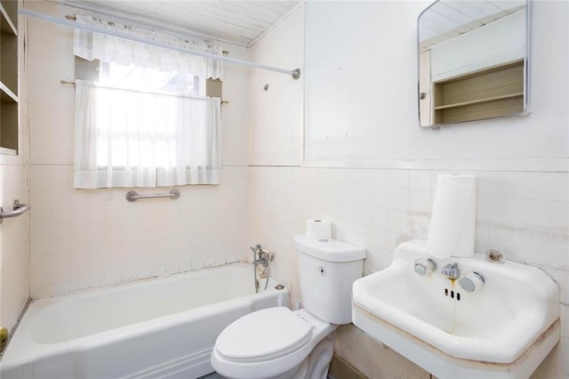 bathroom with tiled shower / bath, toilet, and tile walls