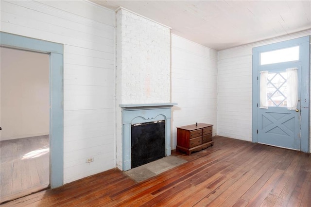 unfurnished living room featuring hardwood / wood-style floors and wooden walls