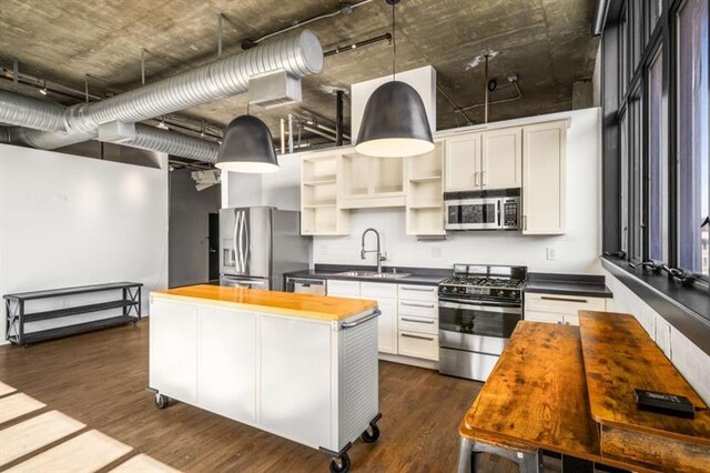 kitchen featuring stainless steel appliances, butcher block counters, dark wood-type flooring, a sink, and a center island